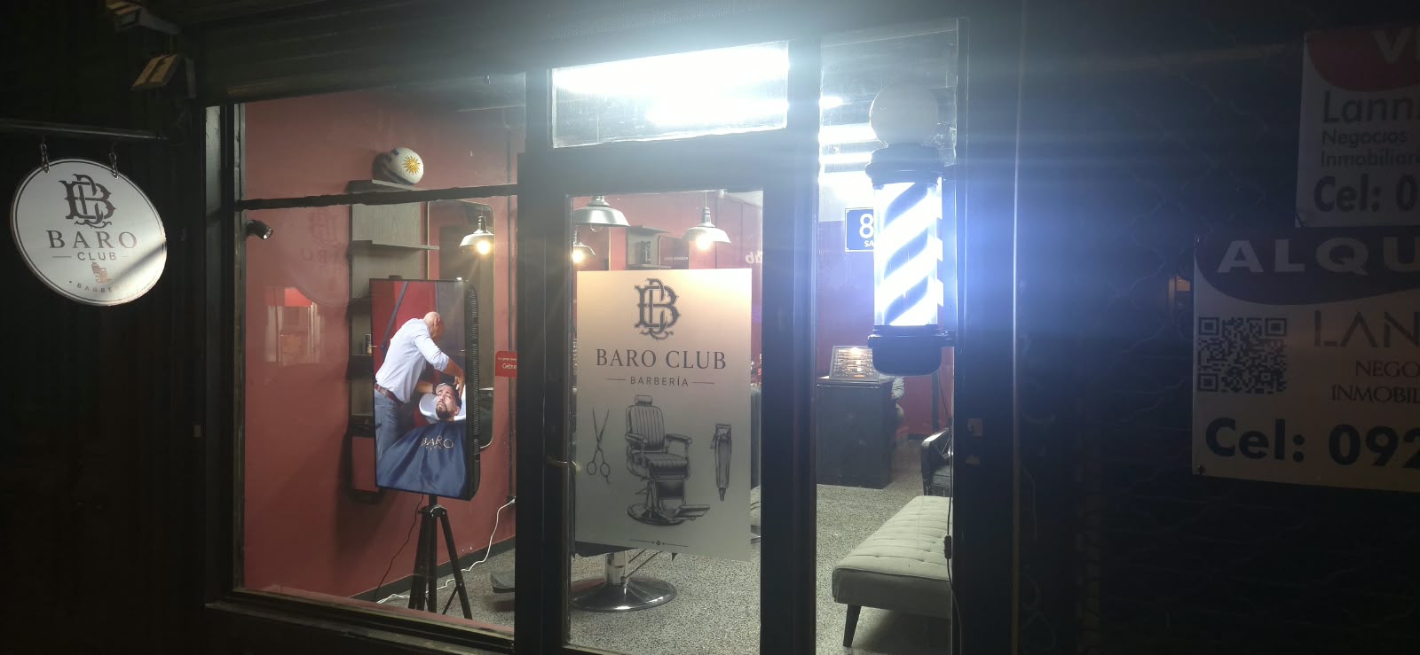 Vidriera de noche con el poste de barbero encendido